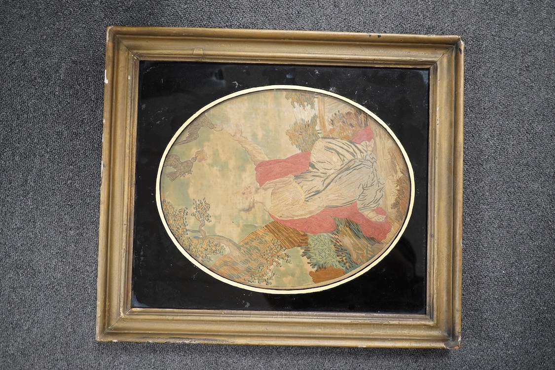 A Regency framed oval silk worked embroidery depicting Elijah being fed by the Ravens, with verre eglomise border, 31cm high. Condition - silk damaged